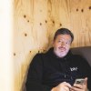 mittelalter Mann in schwarzem Hoodie und mit Handy in der Hand
