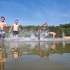 junge Männer laufen und springen in ein natürliches Gewässer