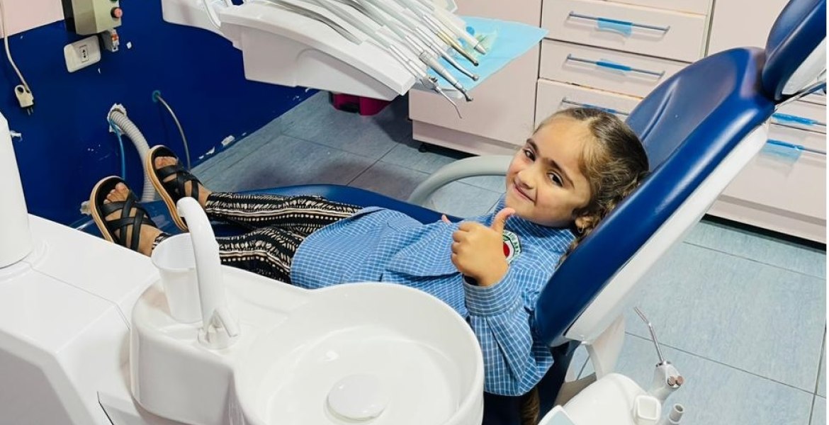 Kind zeigt Daumen hoch auf einer Zahnarzt-Behandlungseinheit