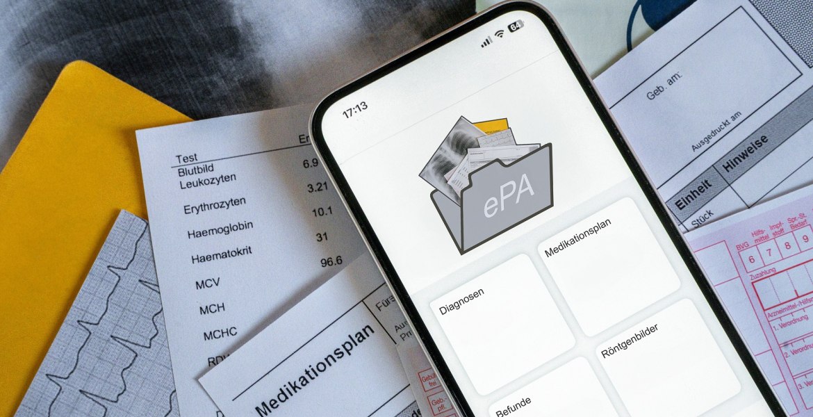 Smartphone mit ePA-App dahinter medizinische Unterlagen in Papier