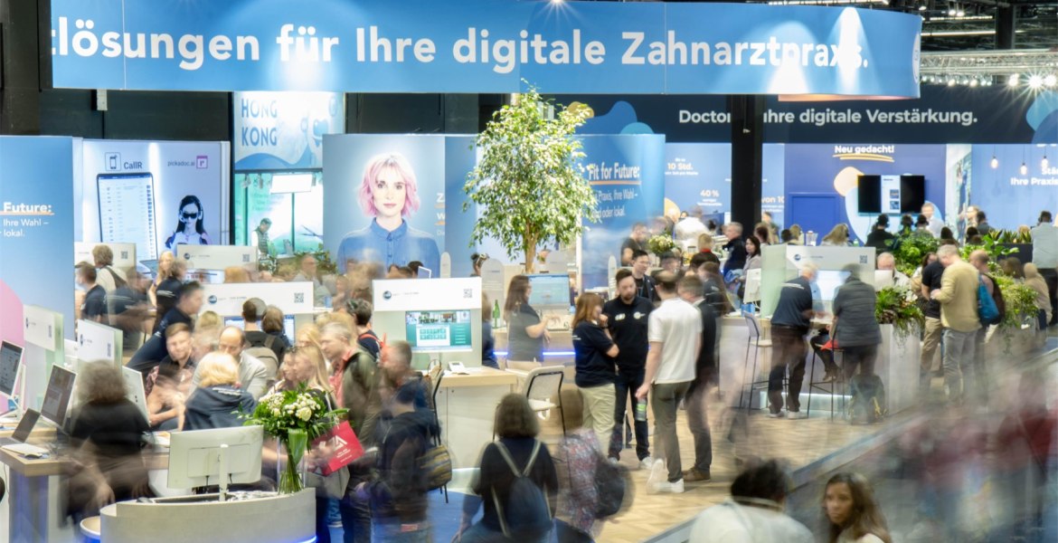 Messestand von CGM mit vielen Besuchern, die teilweise nur verschwommen erkennbar sind