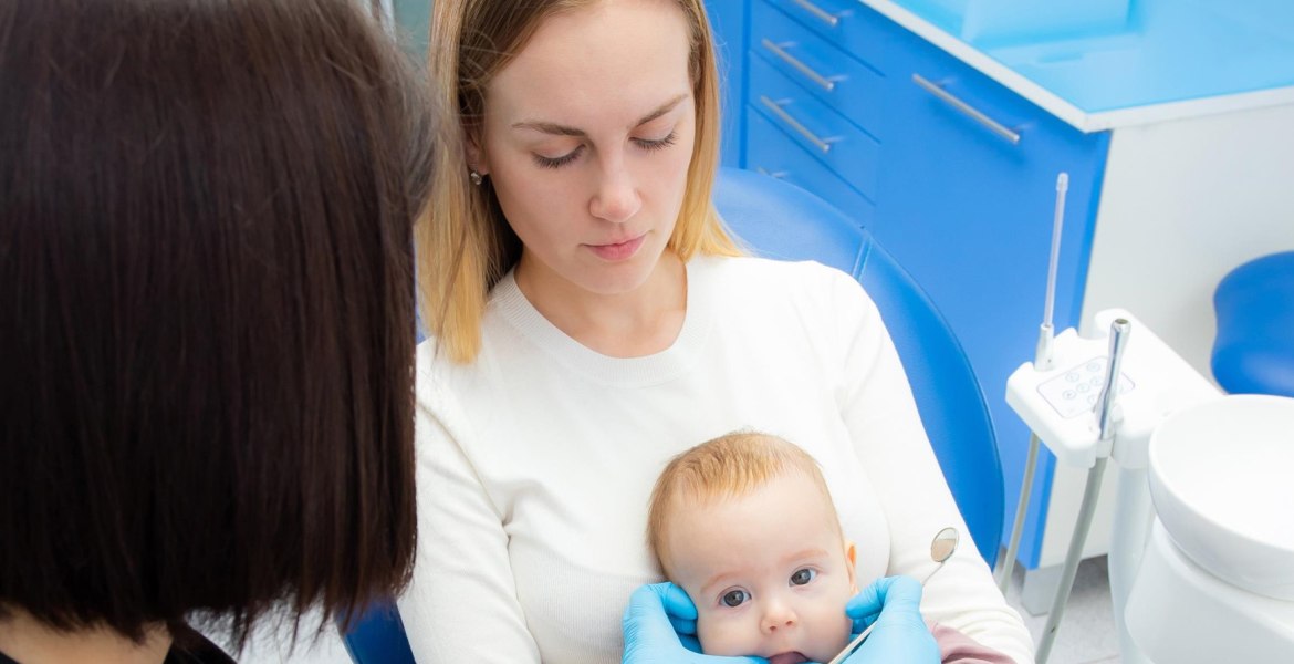 Kleinkund auf dem Schoß der Mutter auf dem Zahnarztstuhl