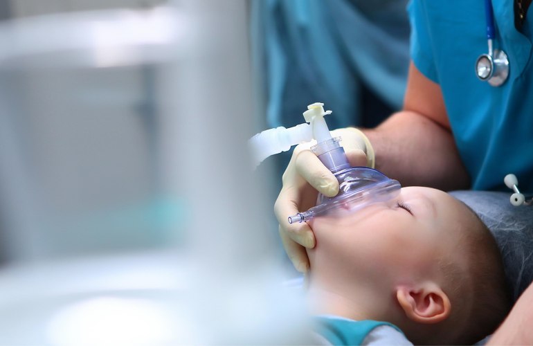 kleiner Junge schlafend mit Anästhesiemaske vor dem Gesicht