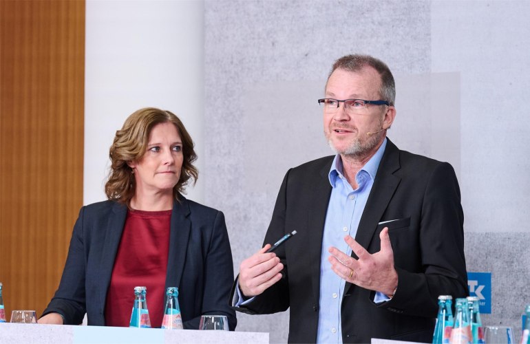 Dr. Jens Baas gestikulierend neben einer Dame stehend