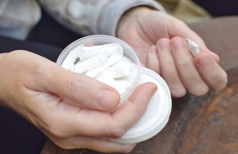 Hand hält eine Schale mit kleinen, weißen, länglichen Beuteln 