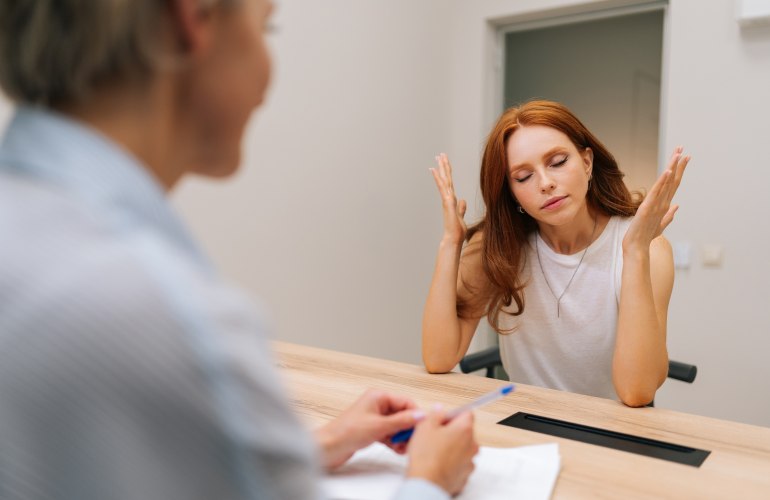 Patientin hebt frustriert Arme neben den Kopf